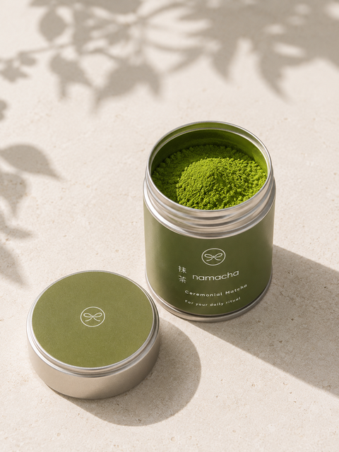Open blik ceremoniële matcha met deksel ernaast, helder jadegroen poeder op een lichte ondergrond